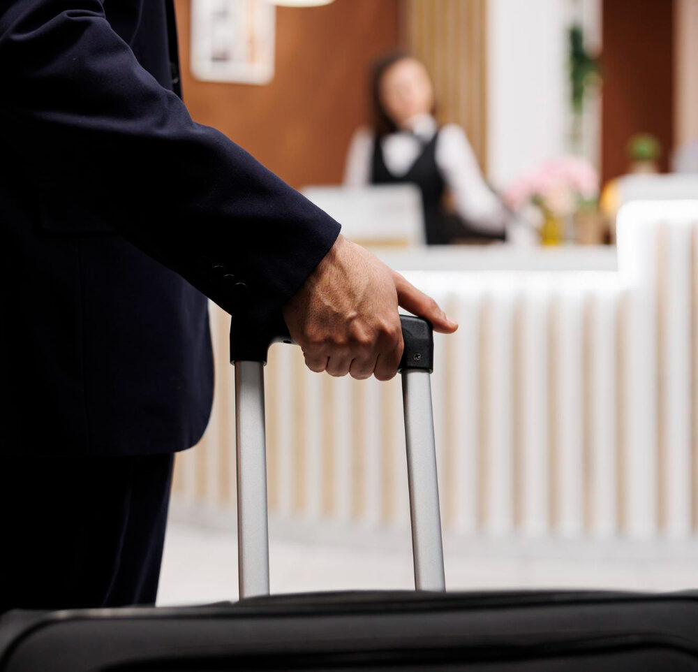 hotel guest entering reception with luggage travelling abroad attend important business meetings entrepreneur approaching front desk check booking accommodation close up e1699020227290