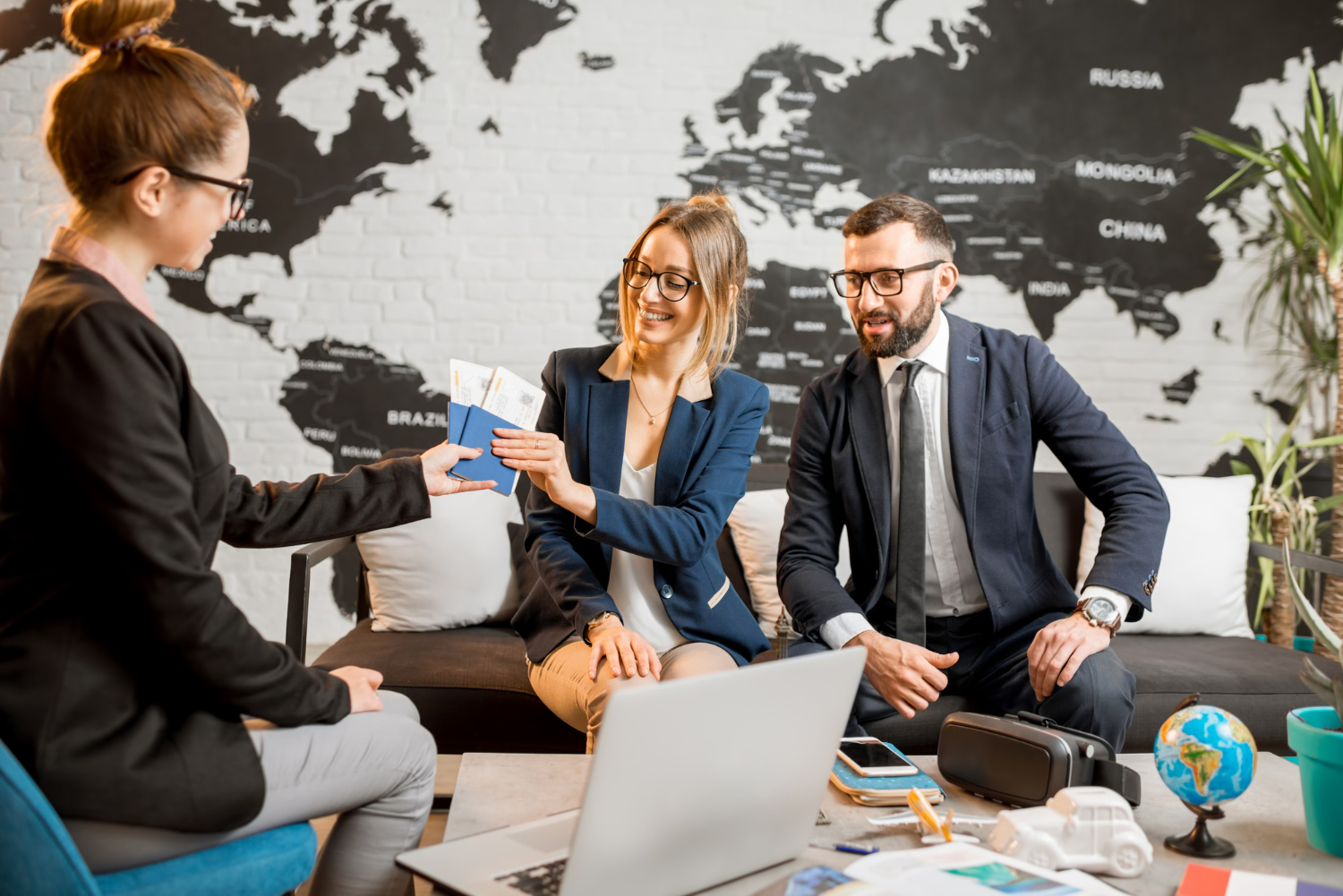 young businesscouple choosing trip with agent sitting travel agency office with world map background